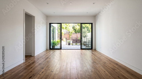 Modern empty living room apartment interior with large glass doors opening to a sunny outdoor terrace