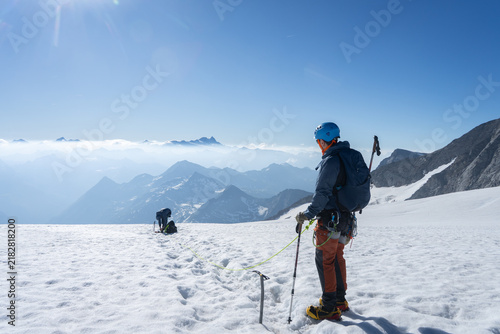 Foto Mountaineer roped up on snowy glacier gazing at vast Alpine panorama, Grossvened