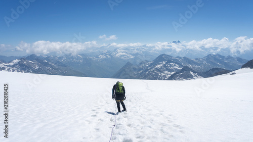 Obraz na plátne Mountain climber hiking across vast snowfield on Grossvenediger glacier with pan