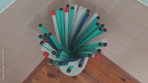 Colorful boomwhackers, plastic percussion tubes, slowly rotating in a basket. Top down view of music education tools on a wooden floor