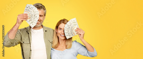 Foto Joyful Caucasian Couple Smiling And Holding Cash While Standing Together At Home, Expressing Happiness And Financial Success In A Bright Setting