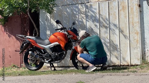 Time lapse of a man dismantling his motorcycle during the day near his garage