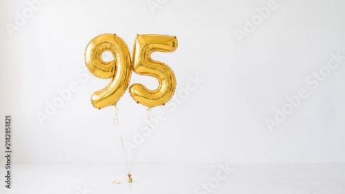 Gold number 95 foil balloons floating on a clean white background with copy space, festive decoration for 95th birthday, anniversary, jubilee and milestone celebration.