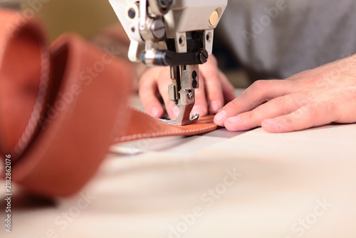 Foto Close-up hands guide red leather under industrial needle