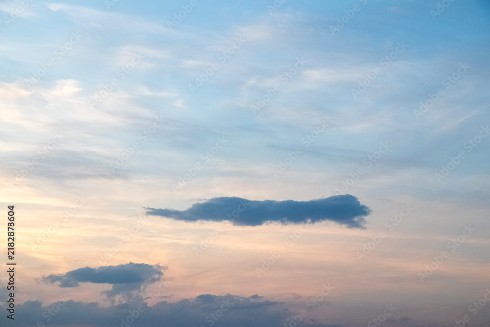 Obraz premium Calm evening sky with thin clouds in pastel blue and peach hues