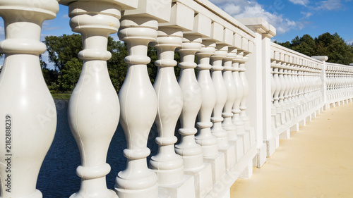 Obraz na płótnie White Stone Balusters in Bridge Railing over River under Blue Sky