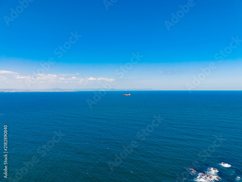 Konstfotografi View of the ocean with clear blue skies and distant land under midday sunlight