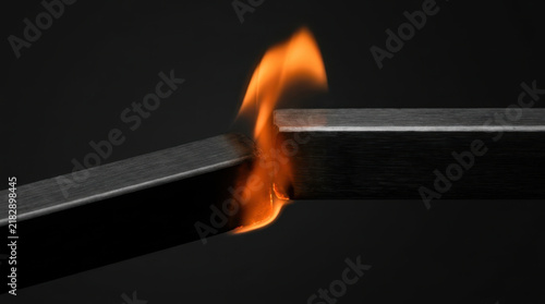Fire meeting metal high contrast black and orange creates dramatic industrial scene with glowing heat, dark texture, and intense energy against