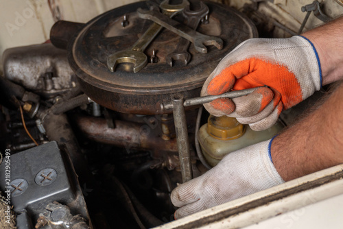 Konstfotografi A focused mechanic repairs an old engine in a cozy garage