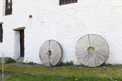 Canvas Print Visitors see old millstones near a white building in Beasain, Gipuzkoa, Basque C