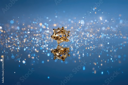 Floating golden dreidel surrounded by soft glowing particles on a smooth gradient blue background. 