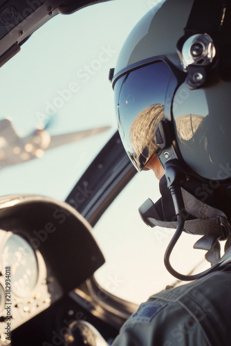 A pilot sitting in the cockpit of an airplane, focused on flight instruments. vertical frame