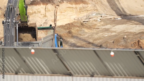Heavy excavator loading earth material into a dump truck during construction site operations, showing excavation work, material transport and infrastructure development