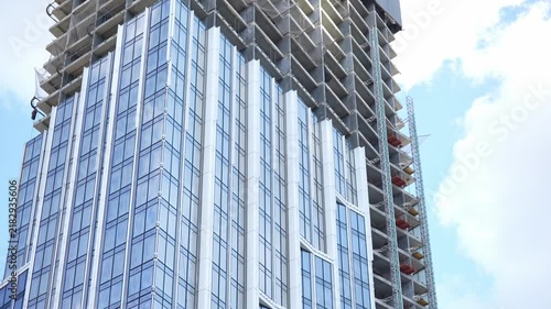 Modern high rise building under construction with completed glass facade sections and ongoing upper floor development, representing urban growth and architectural progress