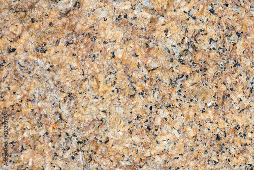 Close up shot of a natural orange granite rock surface texture background. Abstract geological stone pattern backdrop, organic mineral material layer layout.