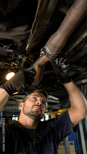 Man inspecting the underside of a raised car