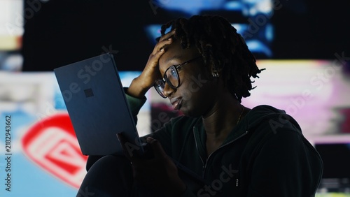 Konstfotografi Woman looks at a laptop with a dull expression, showing boredom and low motivation while browsing the internet as an African American user appears uninterested in notebook content online