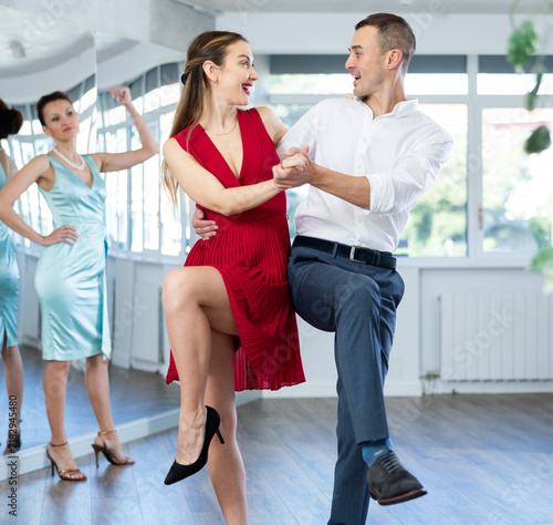Bild auf Leinwand Guy and girl in stage costumes, under guidance of mentor, practice boogie woogie in choreographic studio