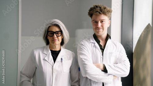 Medical staff, a male and female doctor, standing side by side in a modern clinic, looking at camera
