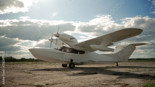 Obraz na płótnie White amphibious aircraft with twin propellers parked on dry airfield under dram