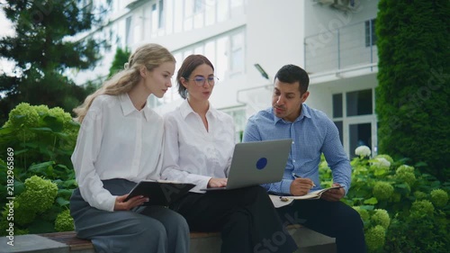 Group of business people working together outside in a garden area during daylight hours