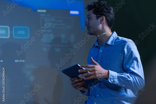 Canvastavla A junior male software engineer in a pale blue shirt holding a digital tablet sm