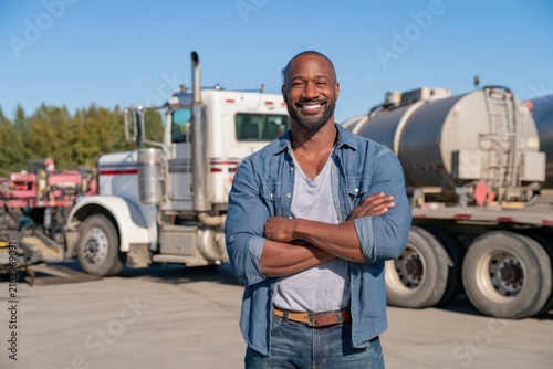 Smiling Black Truck Driver Standing Beside Tanker Truck
