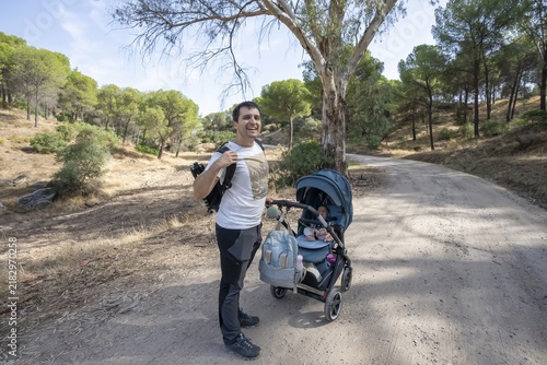 Obraz na plátne Father pushing stroller walking on dirt path