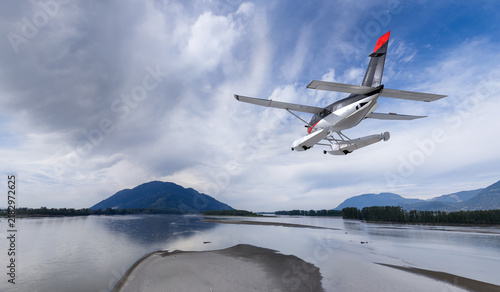 Fotografie Seaplane Flying Over Calm River Near Mountains Above British Columbia Coastline