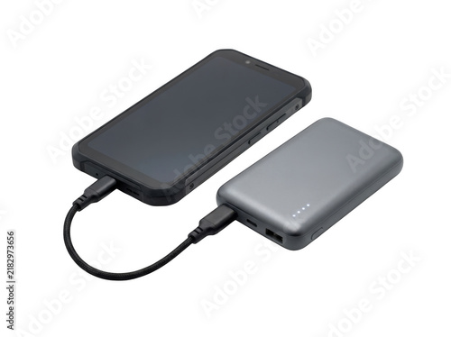 Black smartphone connected to a grey portable power bank with a short black usb cable for charging on a solid black background isolated on a transparent background
