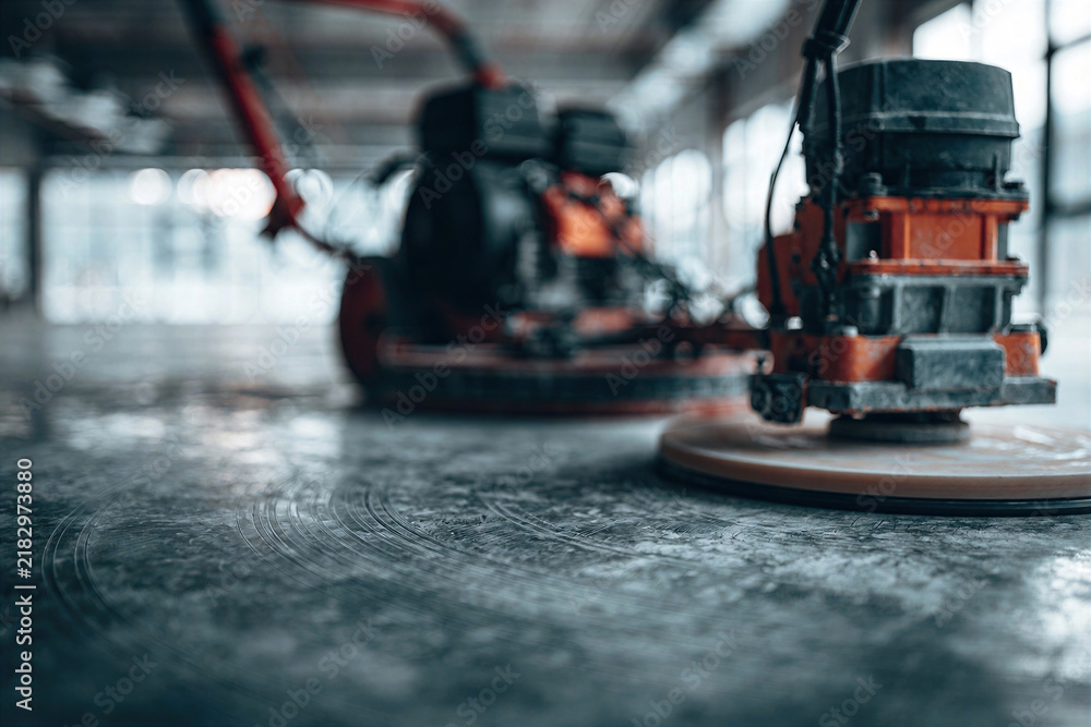 Naklejka premium Power Trowel in Action: Vibrant Construction Tool on Freshly Smoothed Concrete Floor, Bright Interior Setting