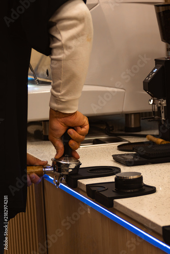 Fotografie Barista tamping fresh ground coffee in portafilter