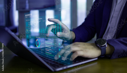 Businessman typing on laptop computer with futuristic holographic digital data interface display