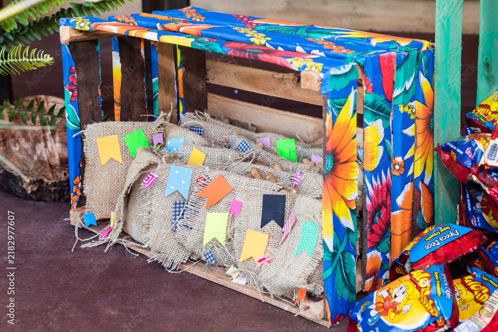 Naklejka premium Rustic Festa Junina decoration with wooden crates, burlap bags and colorful mini flags
