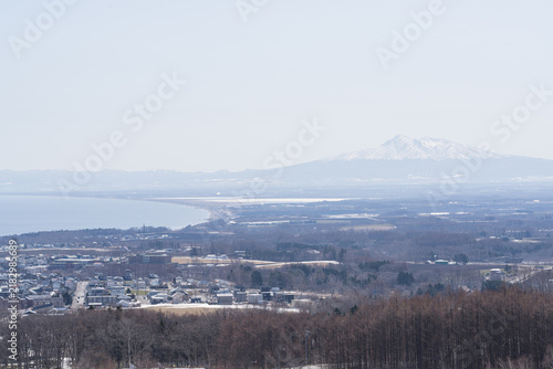Fotografía Snow capped volcano rising beyond a coastal plain in early spring