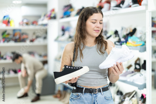 Cuadro en lienzo Girl buys running shoes at store or fair