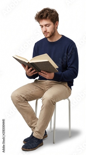 Focused young man sitting on stool reading open book isolated on white background.