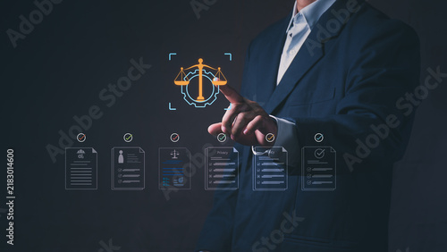 Businessman touches a digital justice scale and gear hologram with approved policy documents. Futuristic corporate technology for legal compliance, data privacy regulation, and business governance.