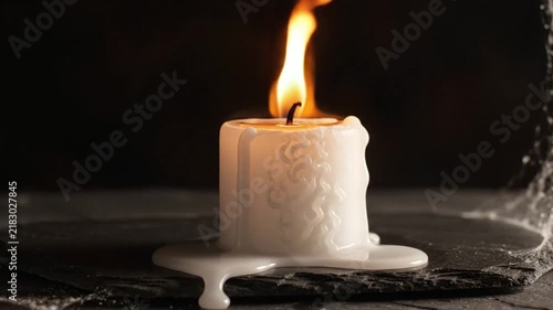 Burning white candle with dripping wax melting slowly in dark environment motion video clip animation style