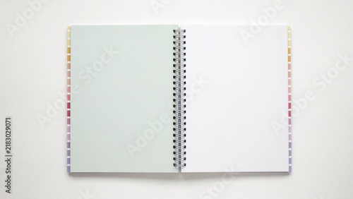 An open spiral bound notebook displays completely blank pages resting on a spotless white background