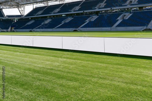 Blank white perimeter advertising board along an empty football stadium pitch
