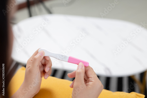 Foto Close-up of women holding home pregnancy test in bedroom, representing pregnancy testing, reproductive health, family planning, fertility awareness, important personal life moment