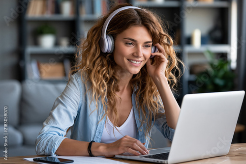 Young woman working on laptop while wearing headphones