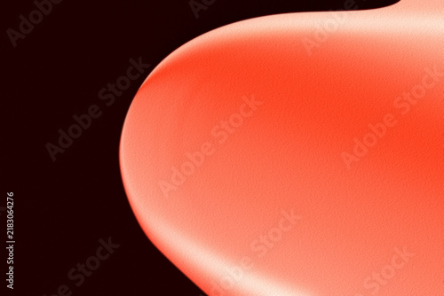 Red rounded form with subtle texture against a dark background