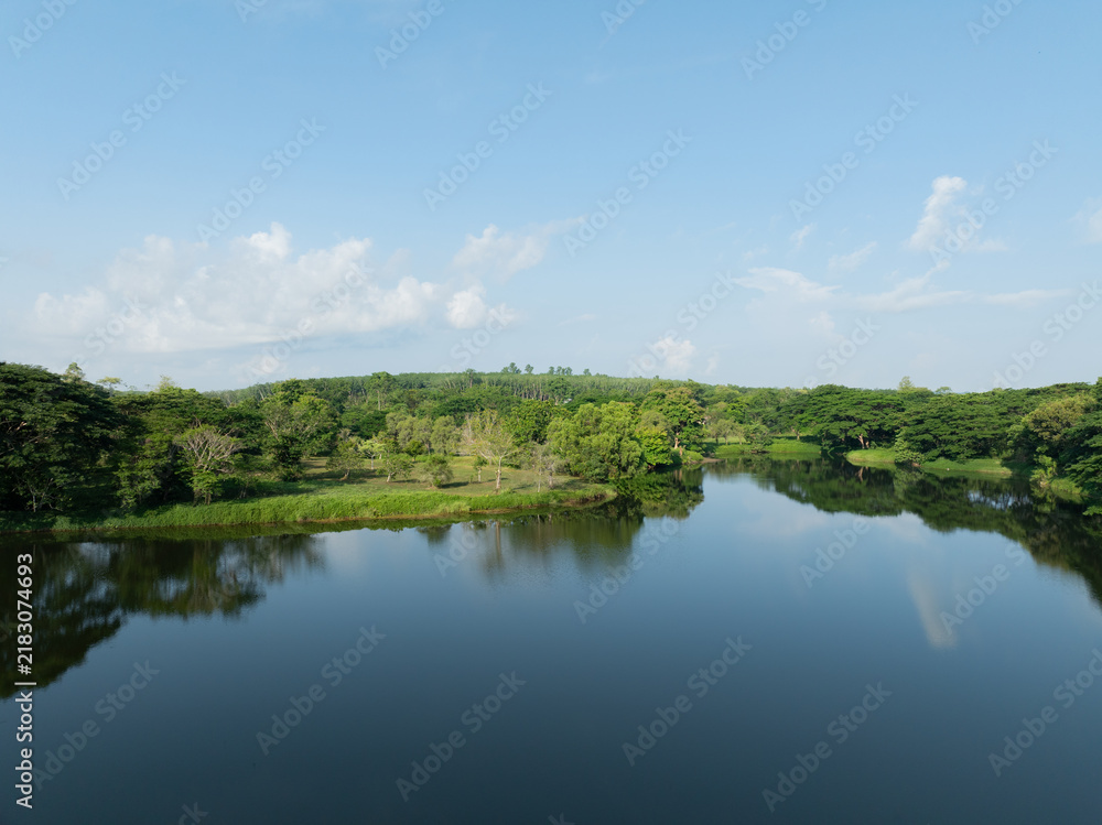 Obraz premium Freshwater lake surrounded by green forest under clear blue morning sky. Water conservation, sustainable resource management, climate action and healthy natural ecosystem. Environmental conservation.