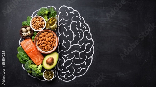 Healthy brain food arranged inside a chalk drawn outline on blackboard featuring salmon walnuts avocado broccoli spinach eggs and olive oil for better cognitive nutrition