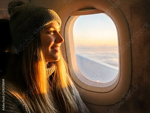 Natural candid smiling woman in airplane window seat during sunset travel category