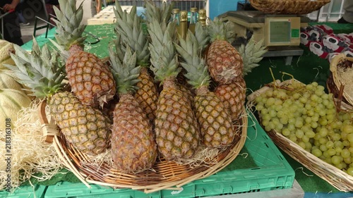 Fresh pineapples and green grapes filling baskets at an outdoor fruit market