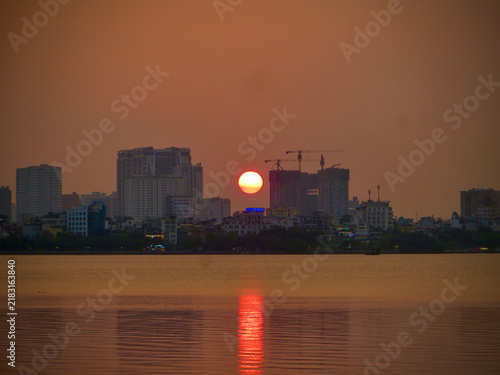 Red Sunset Reflected on Calm Water Below a Distant City Skyline on West Lake in Hanoi, Vietnam