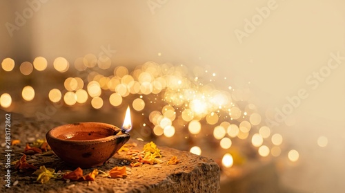 Lit clay diya lamp with marigold flowers and warm bokeh lights, traditional indian festival celebration